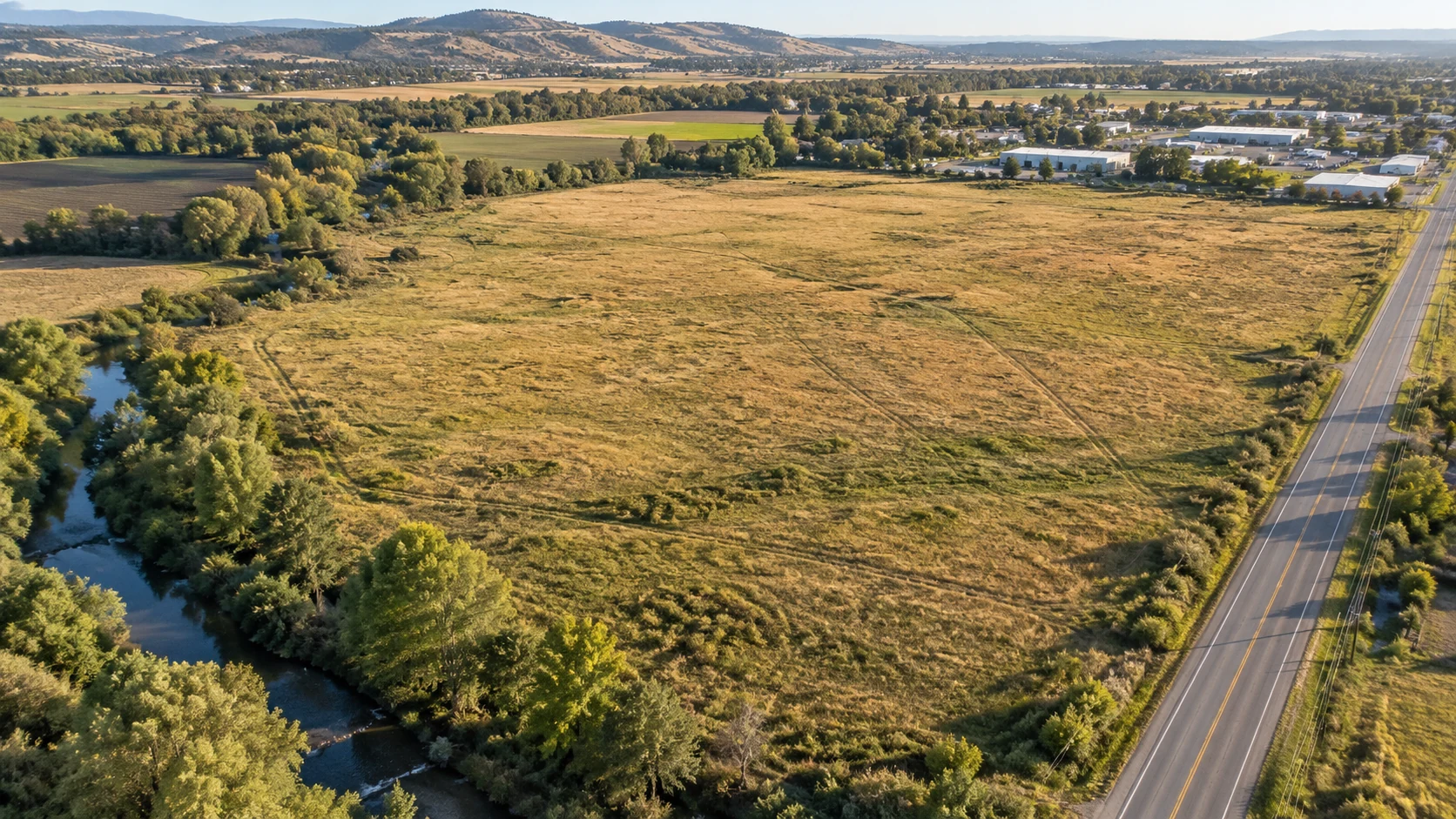 Aerial view of a field beside a waterway and road