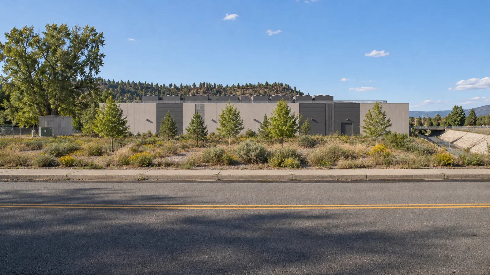 The same street frame with a low data hall set back behind native landscape