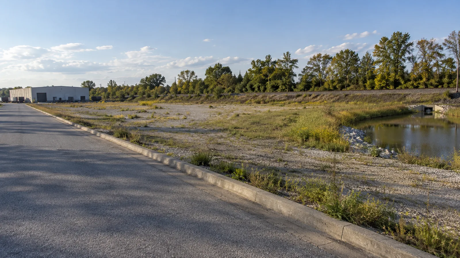 A graded lot beside a retention pond at the end of a service road